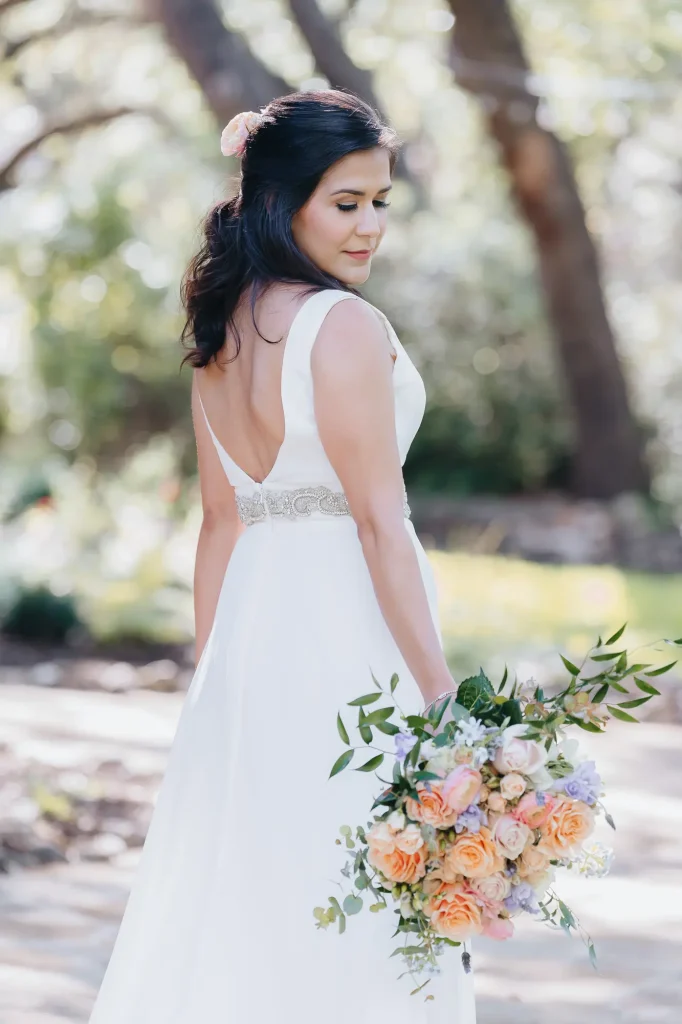 Bride posing for portrait on wedding day, with glam hair and makeup by Marci Madla