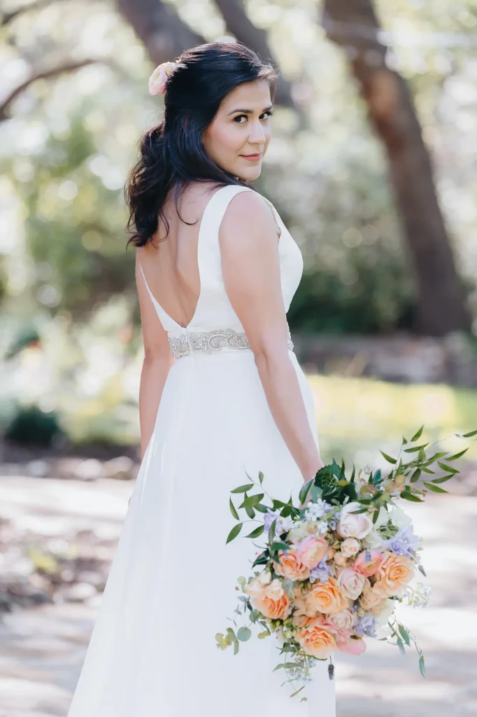 Bride posing for portrait on wedding day, with glam hair and makeup by Marci Madla